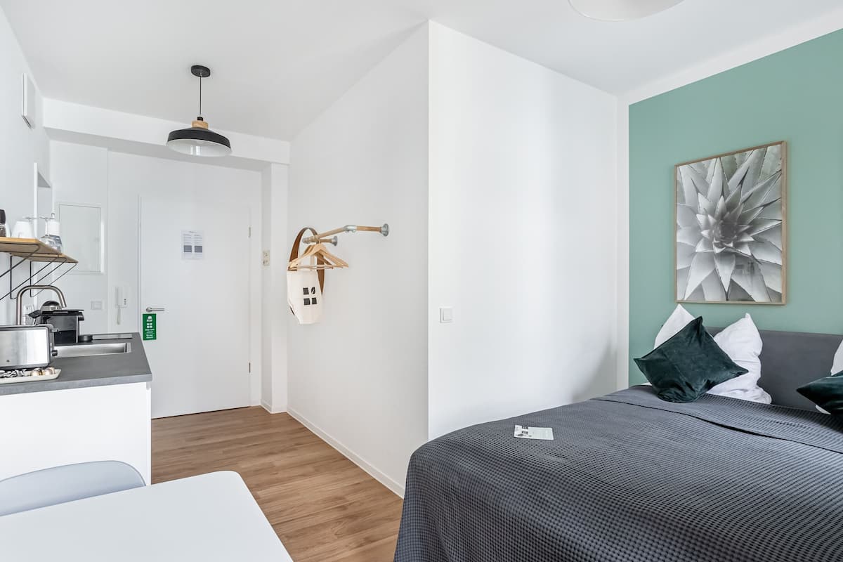 Een moderne hotelkamer met een bed, een bureau en een kitchenette.
