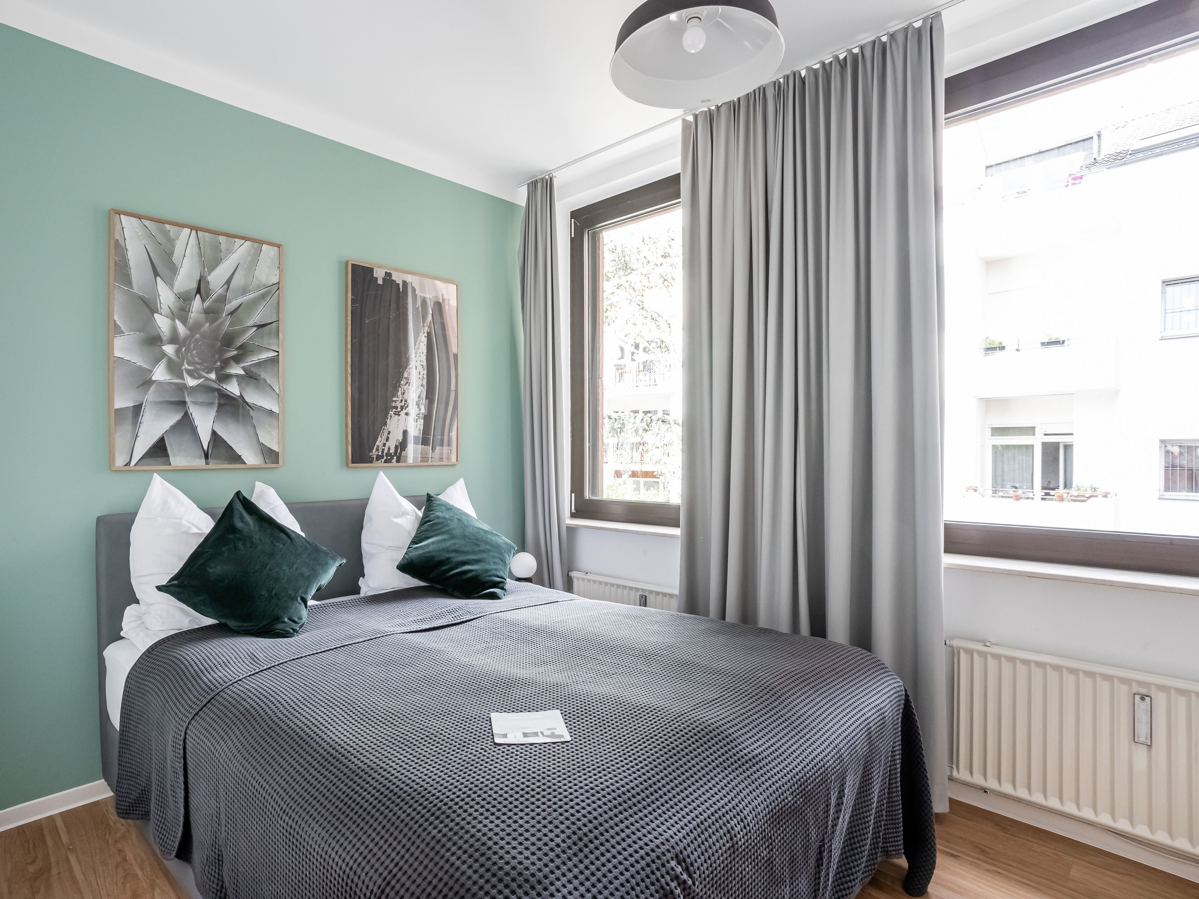 Un dormitorio moderno con una cama grande, ropa de cama gris y dos piezas de arte abstracto en la pared.