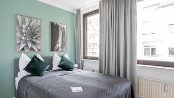 Un dormitorio moderno con una cama grande, ropa de cama gris y dos piezas de arte abstracto en la pared.