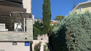 A courtyard with a patio table and chairs, a staircase, and a hedge. - Apartment King (Omisalj)