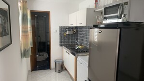 A compact kitchen with a refrigerator, microwave, and a small sink. - Apartment King (Omisalj)