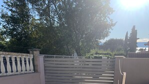 A paved courtyard with a stone floor, a wooden bench, and a planter with plants. - Apartment King (Omisalj)