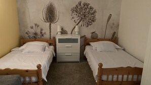 A bedroom with two wooden beds, a nightstand, and a wall mural. - Apartment King (Omisalj)