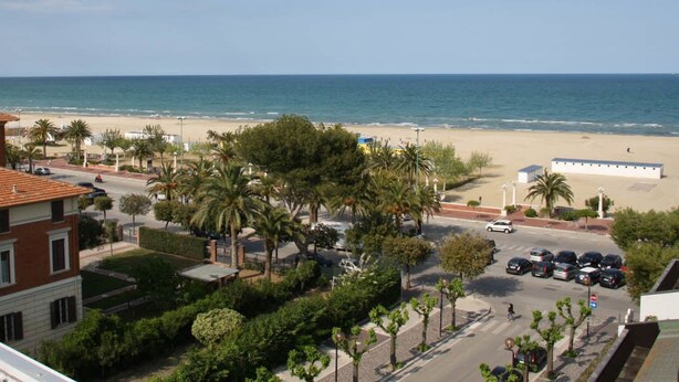 A coastal view with a beach, palm trees, and a parking area. - Hotel Sole (Giulianova)