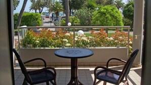 A balcony with two chairs and a small table, overlooking a garden with various plants and trees. - Hotel Sole (Giulianova)