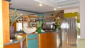 A bar area with a curved counter, shelves with bottles, and decorative plants. - Hotel Sole (Giulianova)