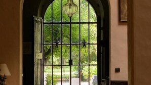 Uma porta arqueada com vista para um jardim, um candelabro e um chão com padrão.