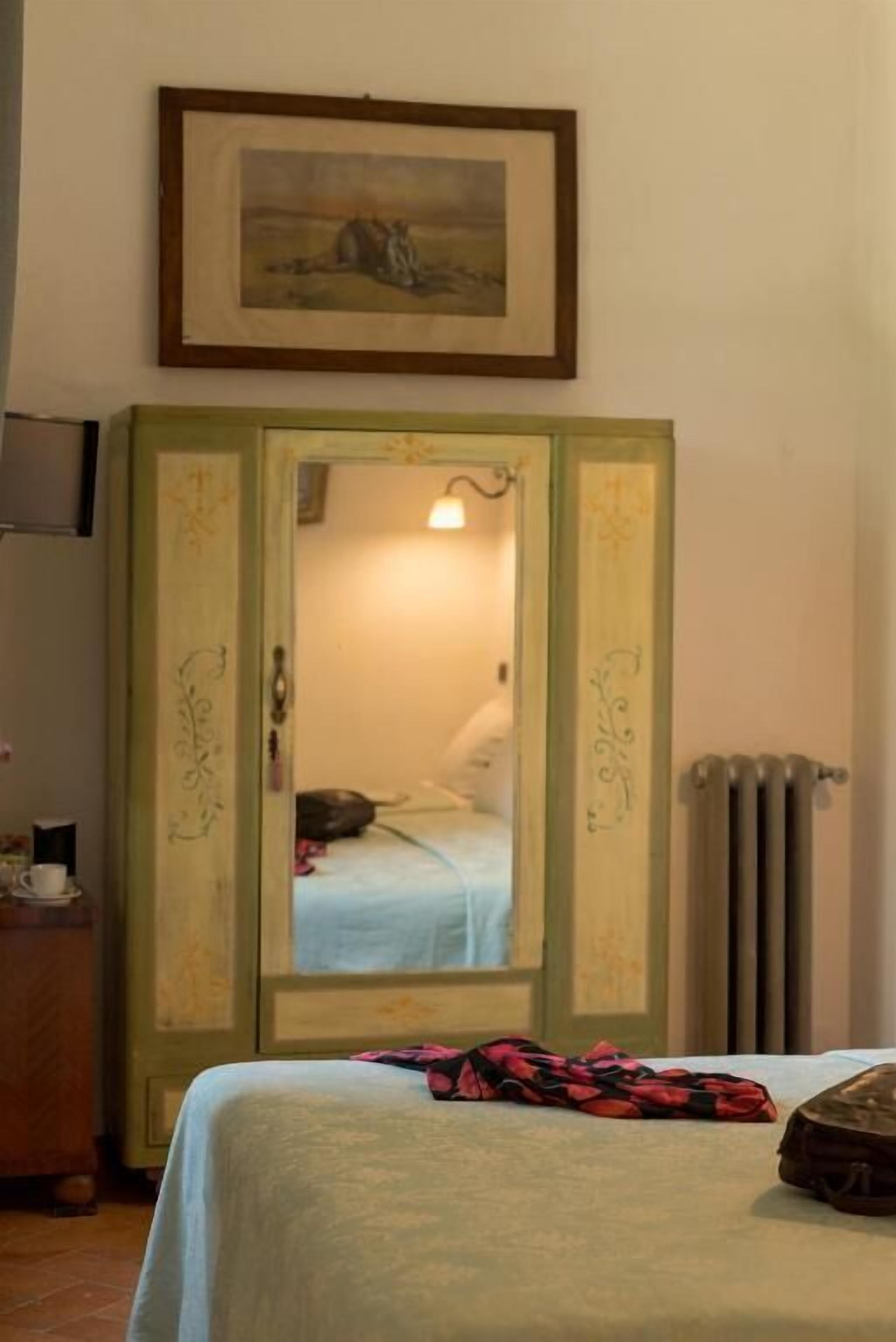 A room with a bed, a dresser, a framed picture on the wall, and a radiator.