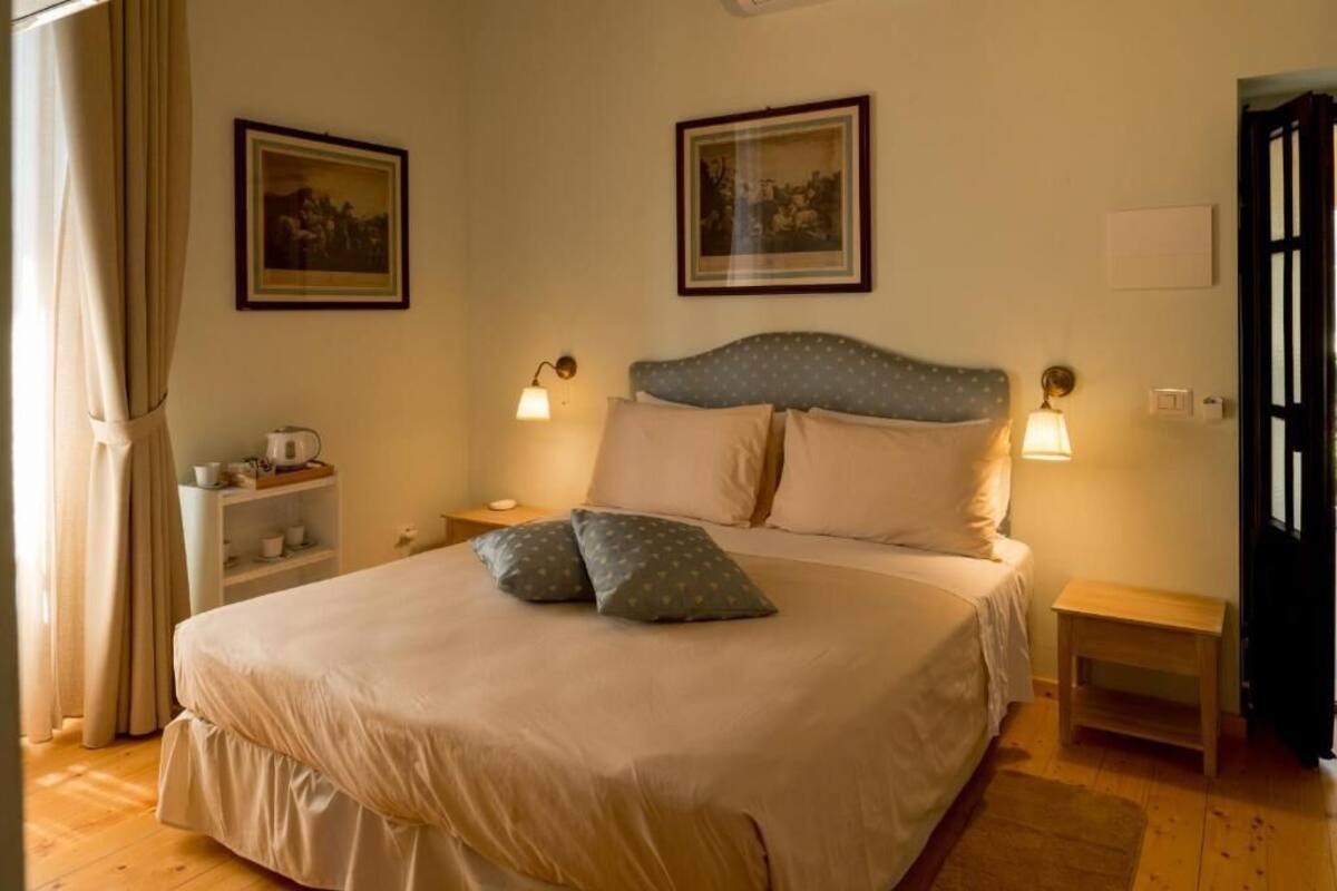 A bedroom with a bed, nightstands, a shelf with cups, and framed pictures on the wall.