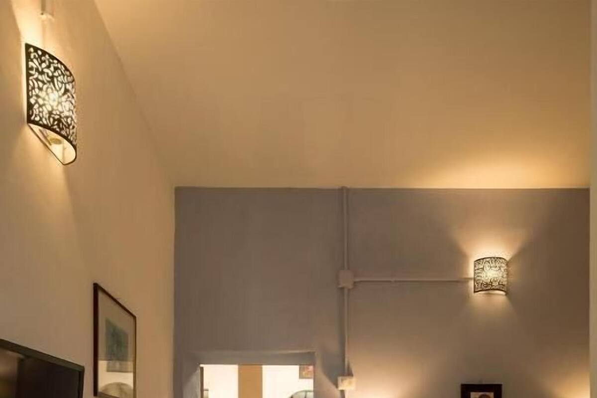 A hotel room with a bed, bedside table, lamp, and a view into the kitchen.