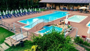 Uma área de piscina com várias piscinas, espreguiçadeiras e uma ponte.