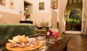 Una mesa de comedor con un plato de comida, dos copas de vino y un arreglo floral.