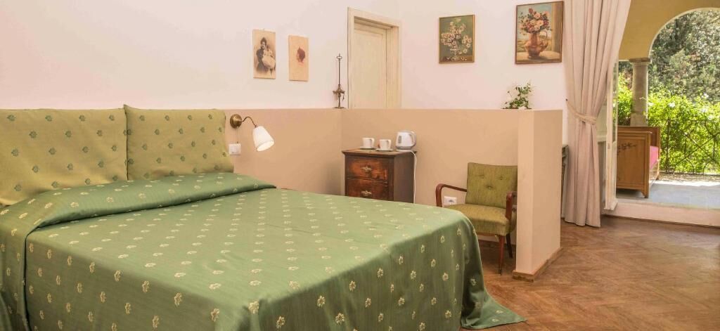 Una habitación con una cama, una silla, una mesita y una puerta.