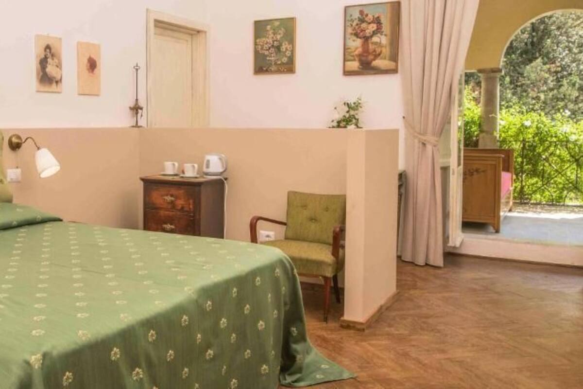 A room with a bed, a chair, a small table, and a door.