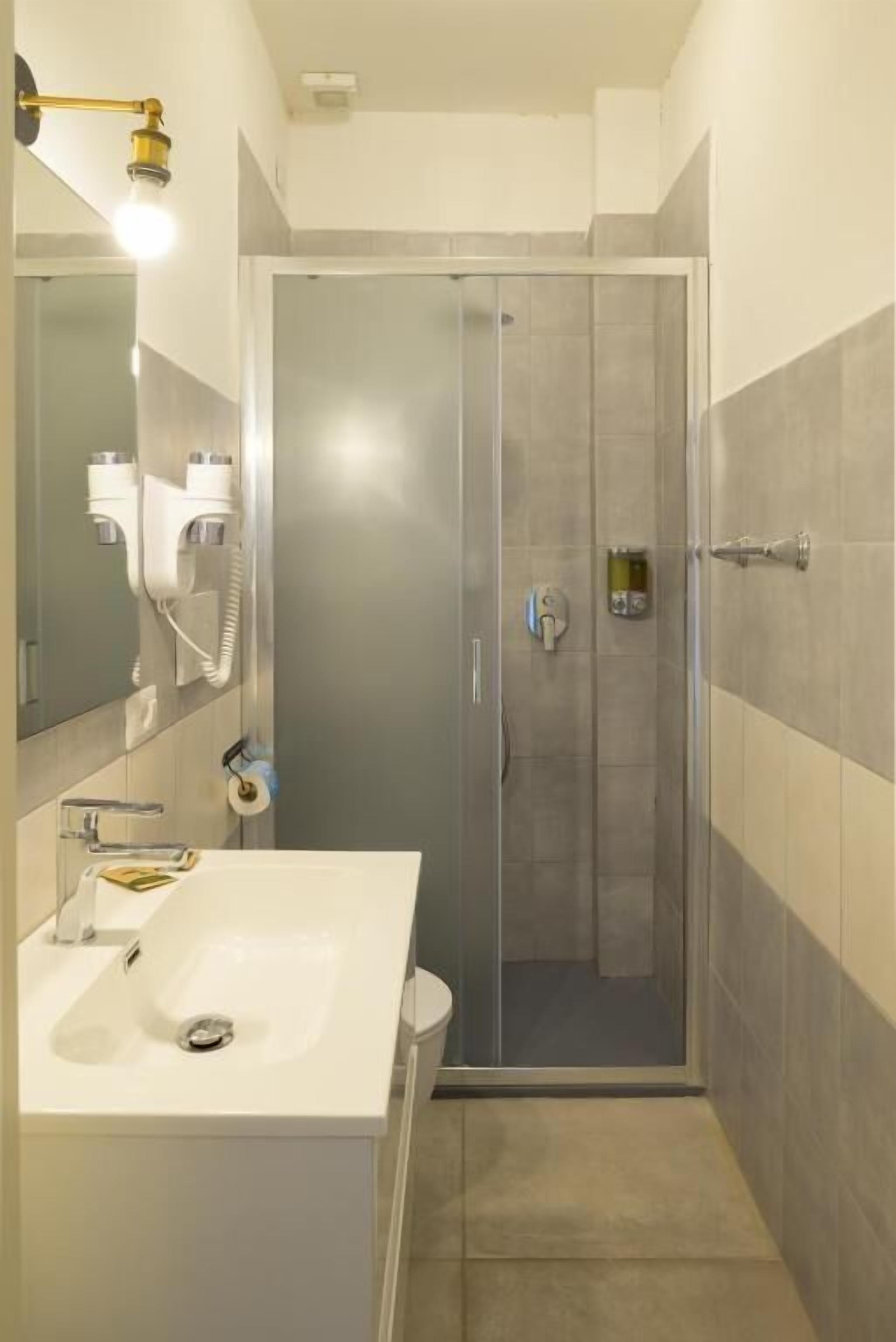 A bathroom with a glass-enclosed shower, a white sink, and a mirror.