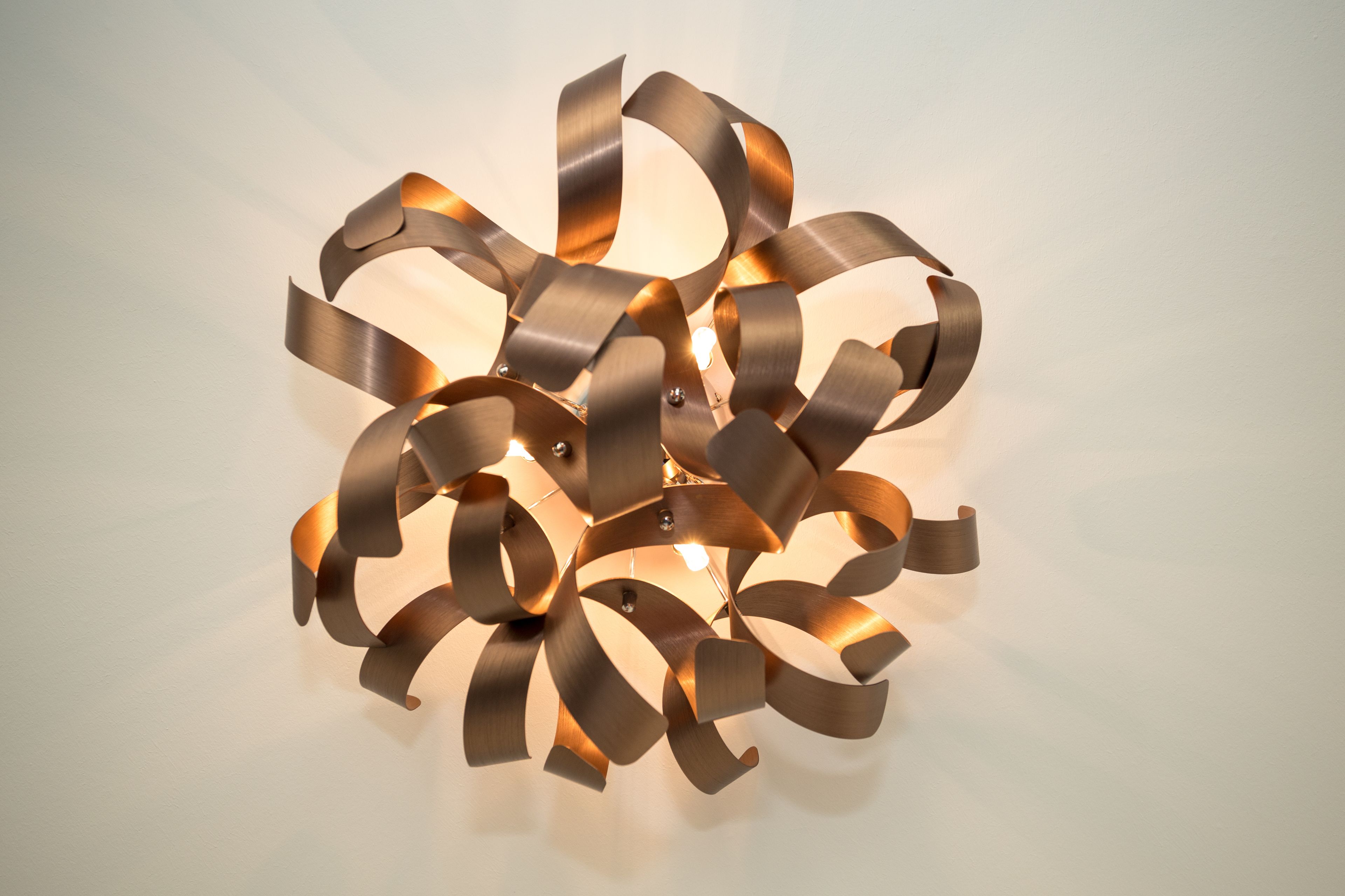 A modern, abstract light fixture with multiple curved metallic elements.