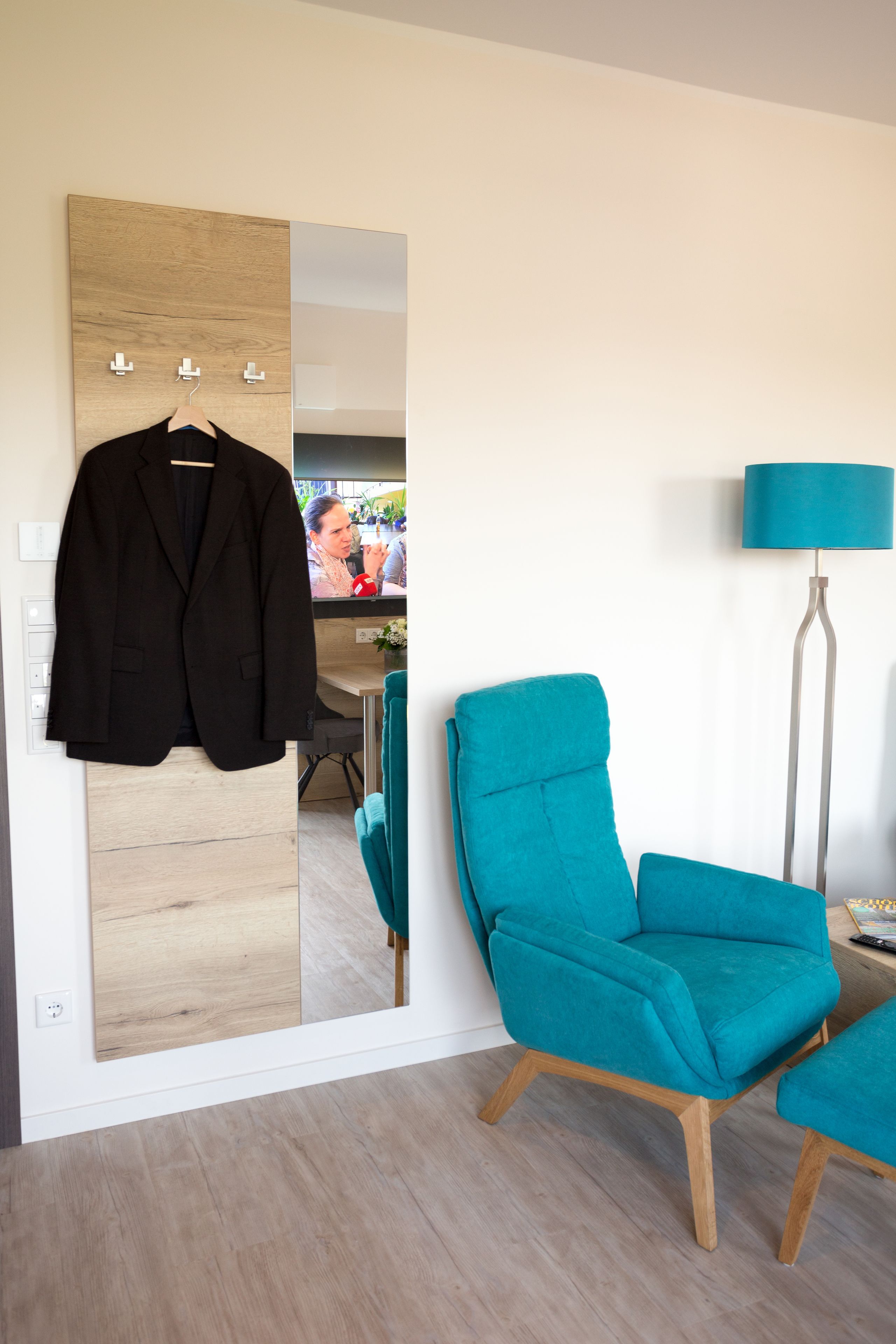A modern room with a wooden wardrobe, a teal armchair, and a floor lamp.