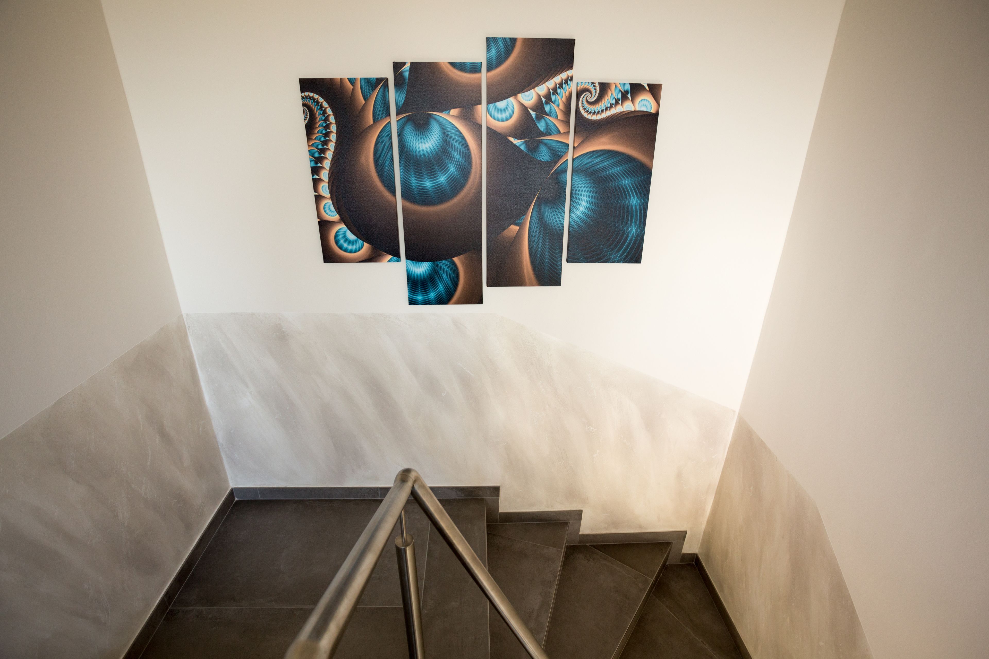 Una escalera de diseño moderno que lleva a una habitación con un cuadro abstracto grande en la pared.