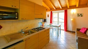 La cuisine est équipée de meubles en bois, d’une cuisinière à gaz et d’un four à micro-ondes. On y trouve également un coin repas avec une table et des chaises, ainsi qu’un canapé dans le salon.