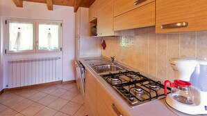 Une cuisine avec des meubles de rangement en bois, une cuisinière à gaz, un évier et une machine à café.