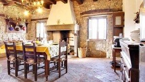 A rustic dining area with a stone wall, wooden beams, and a chandelier. - 3 bedroom villa (8 sleeps) with private pool in Garfagnana (55030 Villa Collemandina)