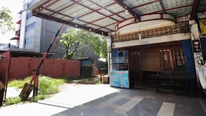 A covered outdoor area with a tiled floor, a bench, and a signboard. - Utama Syariah (Pekanbaru)