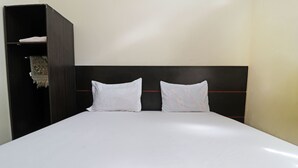 A bed with white bedding and a black headboard. - Utama Syariah (Pekanbaru)