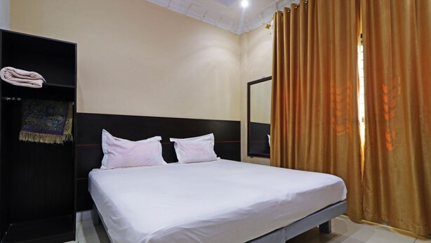 A hotel room with a large bed, a wardrobe, and a mirror. - Utama Syariah (Pekanbaru)