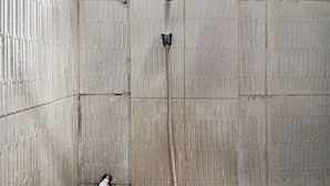 A concrete shower stall with a visible drain and a white pipe. - Utama Syariah (Pekanbaru)