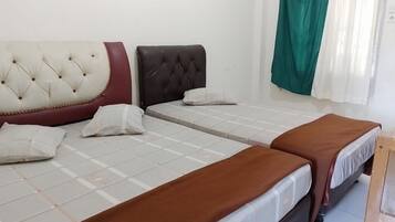 A hotel room with two beds, each with a headboard and pillows.