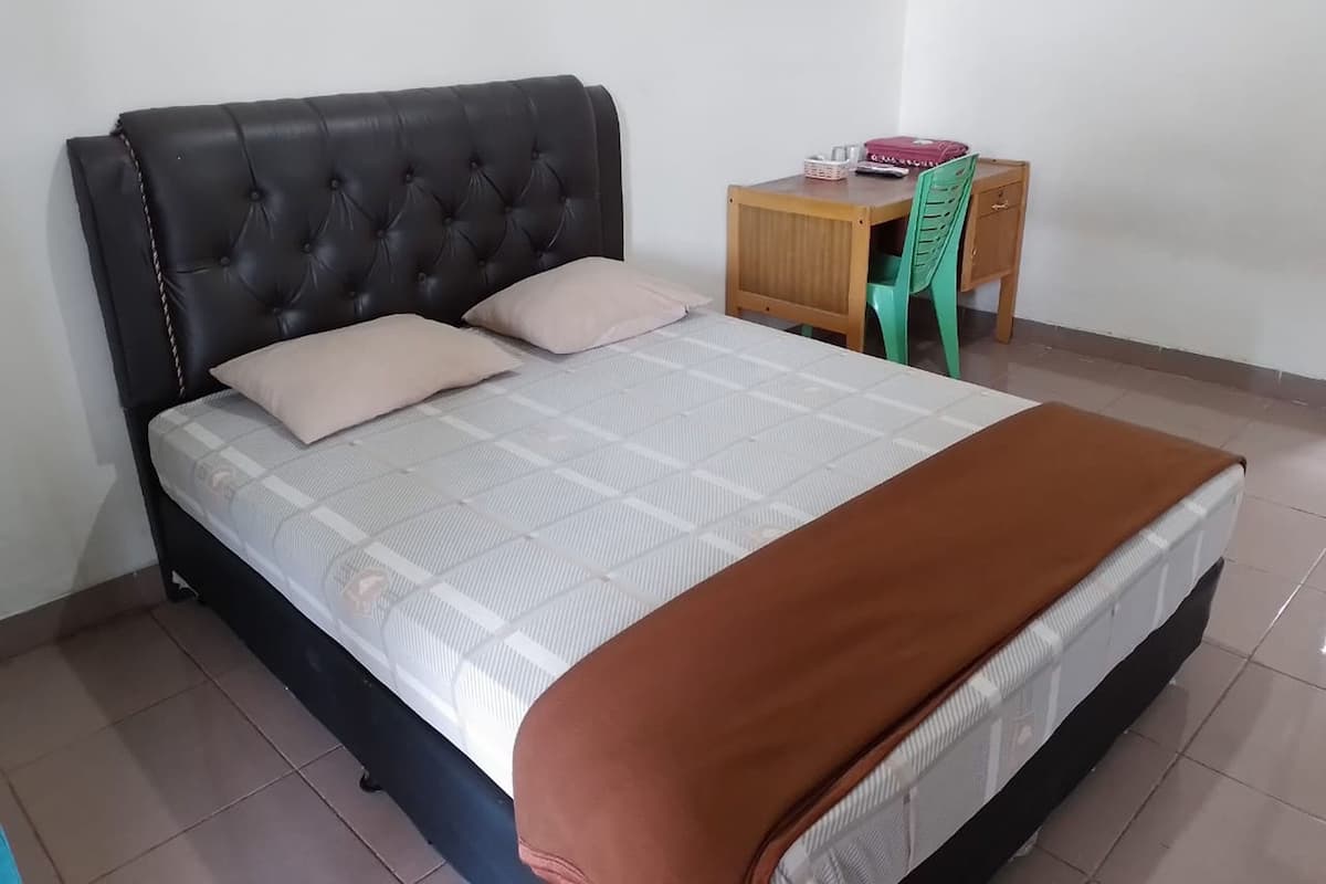 A bedroom with a bed, a nightstand, a chair, and a desk.