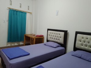 Two single beds with matching bedspreads and a nightstand with a lamp and decorative item.