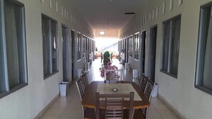 A long corridor with a central dining area featuring a large table and chairs. - Penginapan Syariah (Pekanbaru)