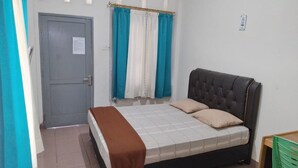A bedroom with a bed, curtains, a door, and a small table. - Penginapan Syariah (Pekanbaru)