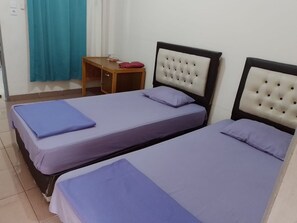 Two single beds with headboards and pillows, a nightstand, and a window with a curtain.