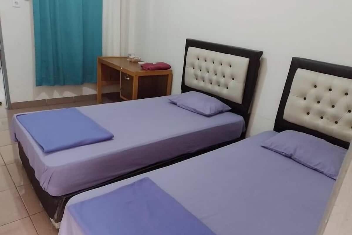 A room with two beds, a small wooden table, and a curtain.