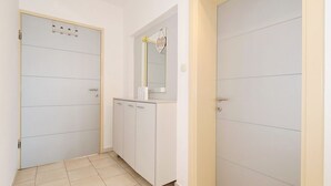 A hallway with three doors, a white cabinet with a mirror, and a light switch on the wall. - Villa Adria (Zadar)