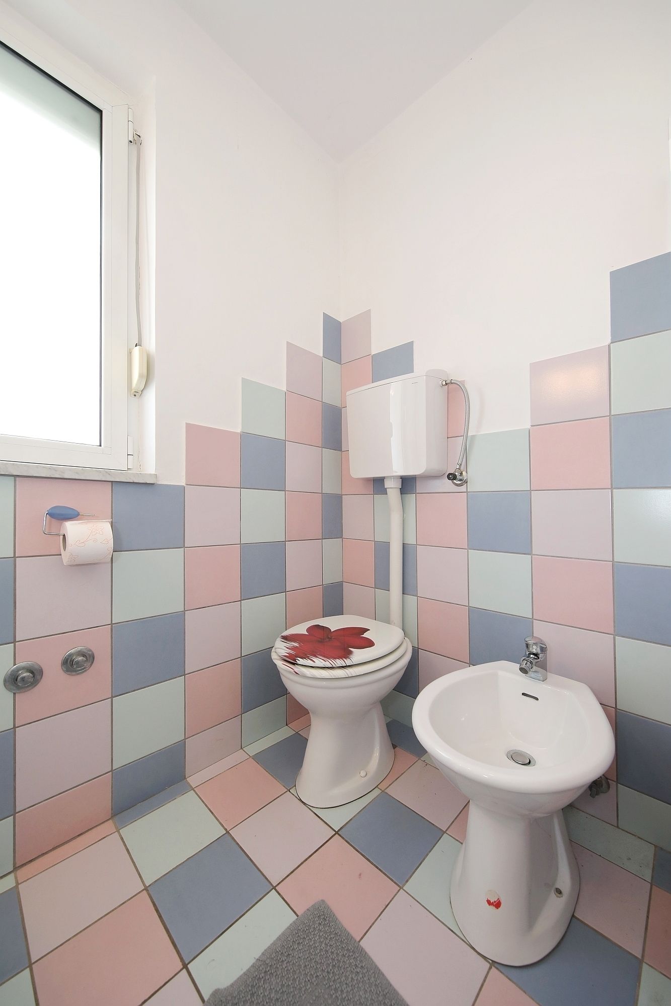 Un baño con inodoro, bidé y ventana.