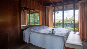 A bedroom with a large bed, wooden walls, and a view of greenery outside. - Monteverde Panoramic House (Monteverde)