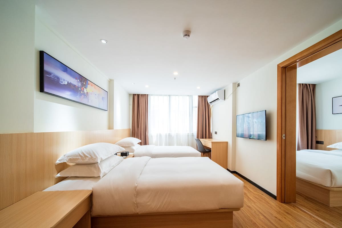 Una habitación de hotel con dos camas, un escritorio, un televisor y una ventana con cortinas.