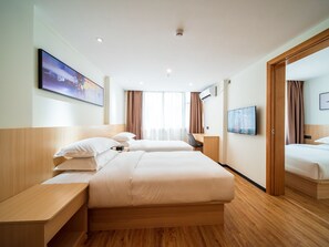Una habitación de hotel con dos camas, un escritorio, un televisor y una ventana con cortinas.