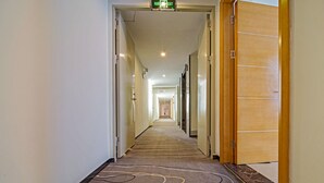 A hotel hallway with carpeted floors, doors on both sides, and a sign indicating an exit. - Guangzhou Changxing Xintiandi Hotel (Guangzhou)