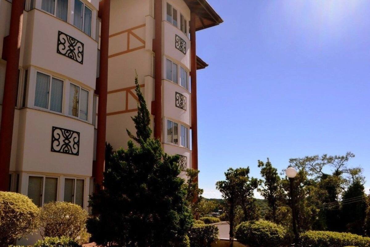 A multi-story hotel with balconies, a clear sky, and well-maintained landscaping.