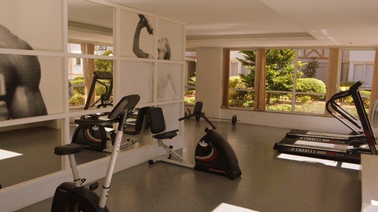 Ein Fitnessstudio mit Trainingsgeräten, großen Fenstern und Blick auf Grünflächen.