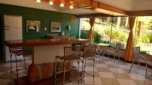 Cocina equipada con refrigerador, microondas y barra con sillas.