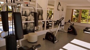 Un gimnasio con varios equipos de ejercicio, como máquinas de poleas, cintas de correr y bicicletas estáticas.