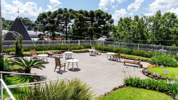 Un patio al aire libre con asientos y mesas, rodeado de follaje y árboles.
