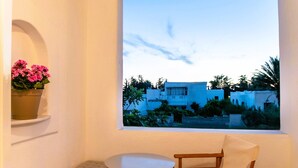 Un balcón con mesa y sillas, una planta en maceta y vistas a edificios y zonas verdes.