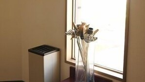 A room with a window, a clear vase with dried flowers on a small table, and a radiator. - Hotel Green Hill Mihama (Mihama)