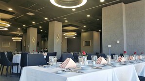 Une salle de conférence équipée de tables rondes, de chaises et d’un éclairage moderne.